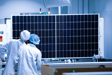 Factory workers lifting new solar panel from production line,and  the technician is checking it in the factory.Intelligent industrial background image.