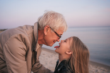 Grandmother plays with granddaughter on the beach