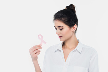 Brunette woman looking at breast cancer awareness ribbon isolated on white