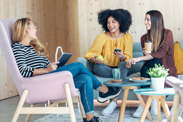 Smart entrepreneur multiethnic women talking while taking a break and showing photos with smart...