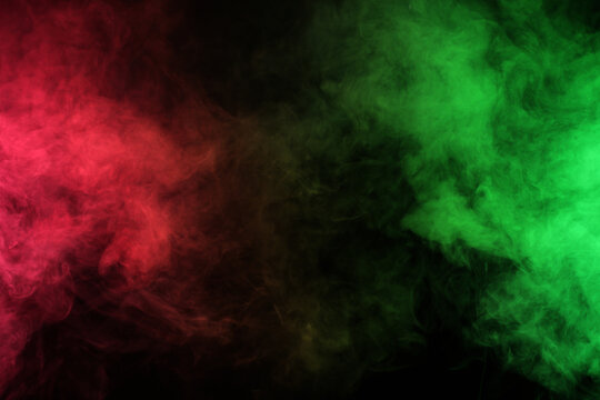 Smoke in red-green light on black background in darkness