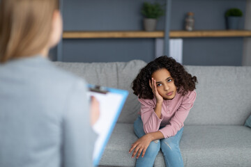 Female child psychologist working with upset black girl, teenager patient talking about her feelings