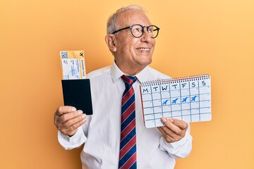 Senior caucasian man going on business trip holding boarding pass smiling looking to the side and staring away thinking.