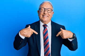 Senior caucasian man wearing business suit and tie looking confident with smile on face, pointing oneself with fingers proud and happy.