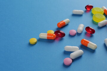 Multicolored medical pills of various shapes on a blue background
