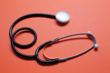 Blue medical stethoscope on orange background. Close-up