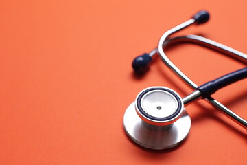Blue medical stethoscope on orange background. Close-up