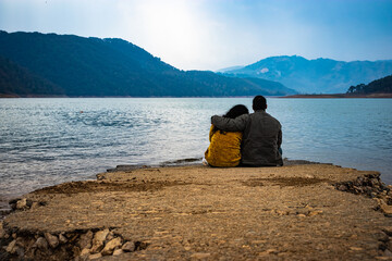 young couple holding each other and looking the serene natural beauty at day from flat angle