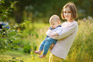 Cute big sister cuddling with her baby brother. Adorable teenage girl holding her new baby boy...