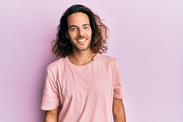 Young handsome man with long hair wearing casual clothes with a happy and cool smile on face. lucky...