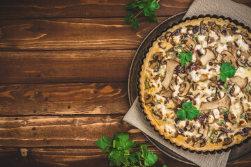 Vegetarian mushroom tart with parsley on wooden table, top view with copy space