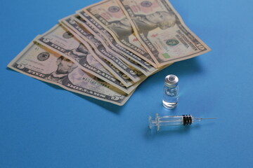 Syringe vial with vaccine and american dollars on blue background