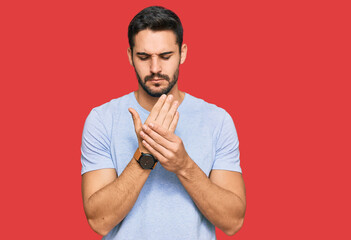 Young hispanic man wearing casual clothes suffering pain on hands and fingers, arthritis...