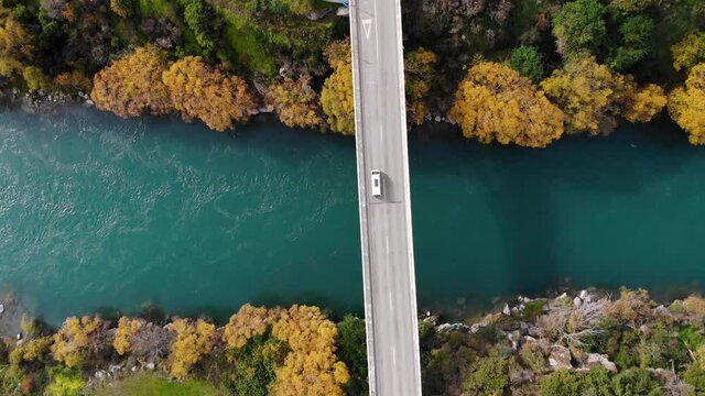 White van driving across the bridge, autumn colours. Aerial look down. New Zealand