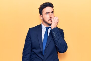 Young hispanic man wearing suit looking stressed and nervous with hands on mouth biting nails. anxiety problem.