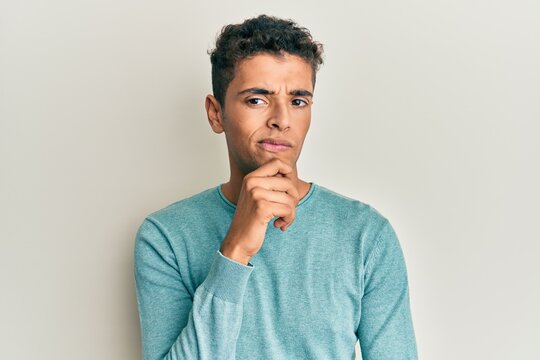 Young handsome african american man wearing casual clothes thinking concentrated about doubt with finger on chin and looking up wondering