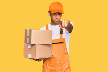 Young handsome african american man holding delivery package pointing with finger to the camera and to you, confident gesture looking serious