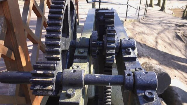 Water Lock Gate Control Gears with Cogwheels On Canal with Waterfall and Rocky Stream underneath on Bright Sunny Morning
