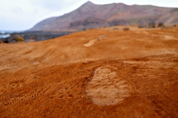 Human footprints in red volcanic soil.