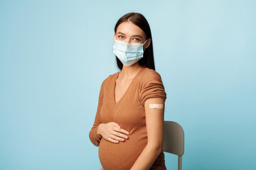 Vaccinated Pregnant Woman Wearing Protective Face Mask On Blue Background