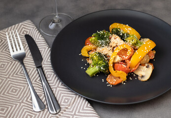 Delicious salad made of broccoli, cherry tomatoes, yellow pepper, mushrooms and pieces of chicken breast decorated with sesame seeds. Healthy food for dinner or lunch. Cooking concept.