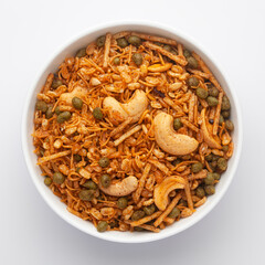 Close-Up of Hot spicy Kashmiri Mixture (Namkeen) snacks in a white ceramic bowl made with dry fruits, peanuts,  Indian spicy snacks, Top View