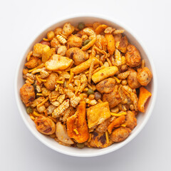 Close-Up of Indian spicy snacks (Namkeen) - (All in one) in a white Ceramic bowl, made with fried peanut, corn flakes, sweet pea, pulses, cashew nuts. Top View