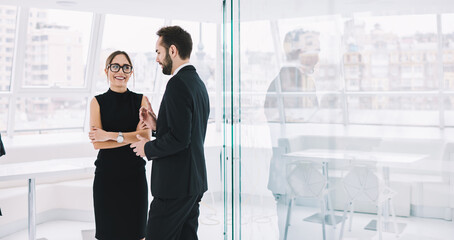 Happy male and female business partners enjoying collaborative brainstorming and friendship during working time in office company, smiling employees in formal clothes have positive conversation