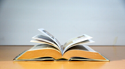 Open Book on wooden table with greyish blue color background, back to school concept