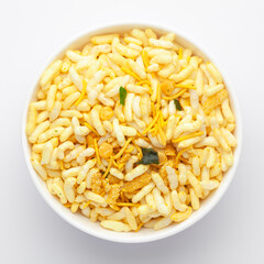 Close-Up of Crunchy Murmura in a white Ceramic bowl, made with Puffed Rice and Curry leaves. Indian spicy snacks (Namkeen), Top View
