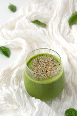 green smoothie in a glass on a white tablecloth