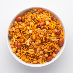 Close-Up of Hot spicy Nav Ratan snacks in a white Ceramic bowl, made with red chili, peanuts. Indian spicy snacks (Namkeen), Top View                                                                  