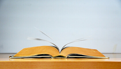 Open Book on wooden table with greyish blue color background, back to school concept