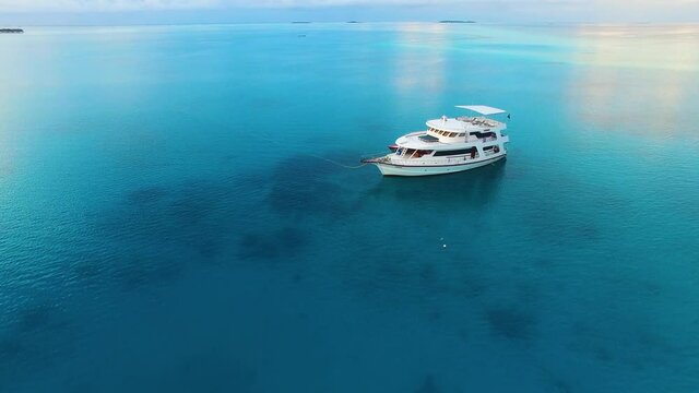 Aerial view of yacht and small boat moored in the middle of turquoise, crystal clear water. Tropical landscape, lagoon in paradise. Diving in Seychelles, Maldives, Bora bora.