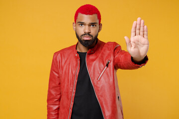 Young african dark-skinned serious strict man 20s with funky trendy pink hairdo wearing red leather...