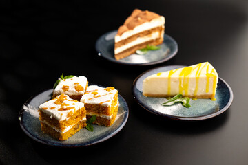 A few different desserts, assorted sweets on plates on a black background. Vanilla classic and chocolate cake, carrot cake.