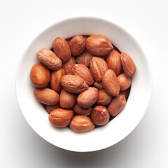 Macro Close up of organic red-brown peanuts (Arachis hypogaea) inside a white Ceramic bowl, Top View