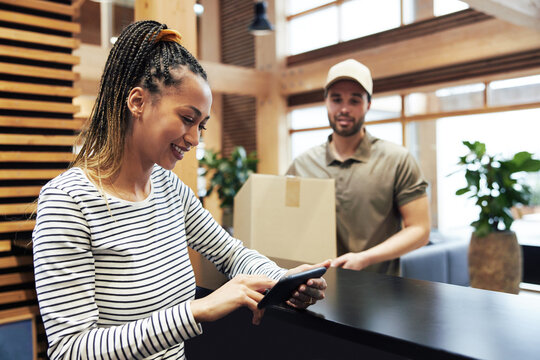 Smiling young businesswoman signing for a courier package
