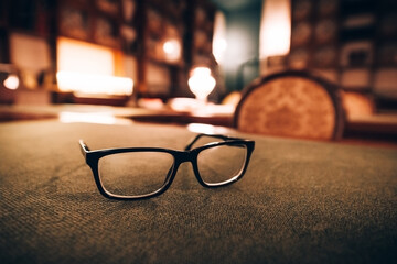 The blurred background of the old library room,the bookshelves of ancient books.Glasses on the...