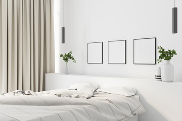 Modern cozy bedroom with white linen and a white wall with three blank posters.