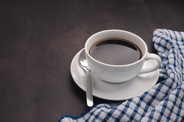 A cup of hot fresh black coffee and cloth on the old kitchen table. Top view with copy space for your text. Concept of the morning, energy, and cheerfulness
