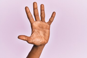 Arm and hand of black middle age woman over pink isolated background counting number 5 showing five...