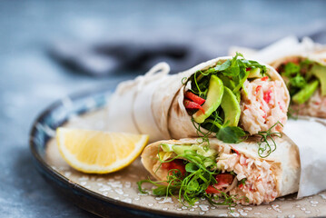 Fresh and healthy wrapped tortilla with crab salad, cucumber, avocado, pepper and green herbs