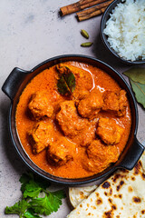 Chicken tikka masala in spicy sauce with rice and chapati bread, dark background, top view, close up. Indian cuisine concept.