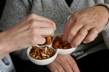 Senior woman having nuts and dried fruits for snack. 
Healthy dieting and smart snack choice.