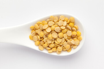 Macro Close-up of Organic arhar dal (Cajanus cajan) on a white ceramic soup spoon. Top view