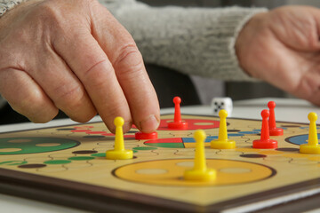 Senior woman playing board game with granddaughter or care giver. Preventing Alzheimer’s disease...