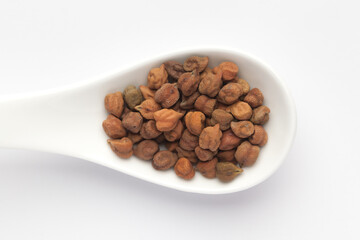 macro Close-up of Organic chana or chickpea (Cicer arietinum) or whole white Bengal gram dal on a white ceramic soup spoon. Top view