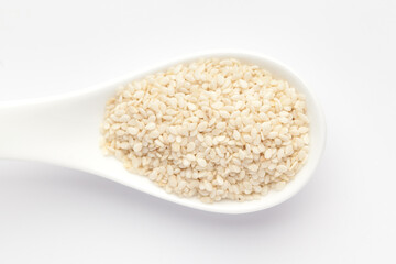 Macro Close up of Organic White  Sesame seeds(Sesamum indicum) polished or white Til without the shell on a white ceramic soup spoon. Top view