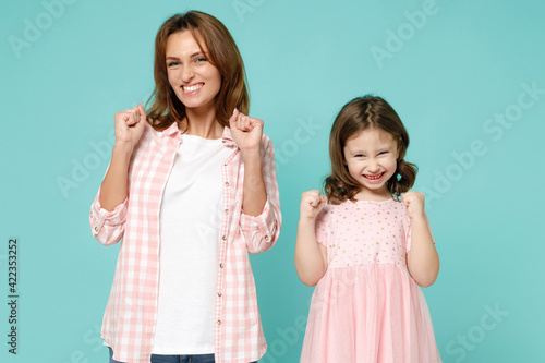 Happy woman in pink clothes have fun child baby girl 5-6 years old. Mommy little kid daughter doing winner gesture celebrate isolated on pastel blue background studio Mother's Day love family concept